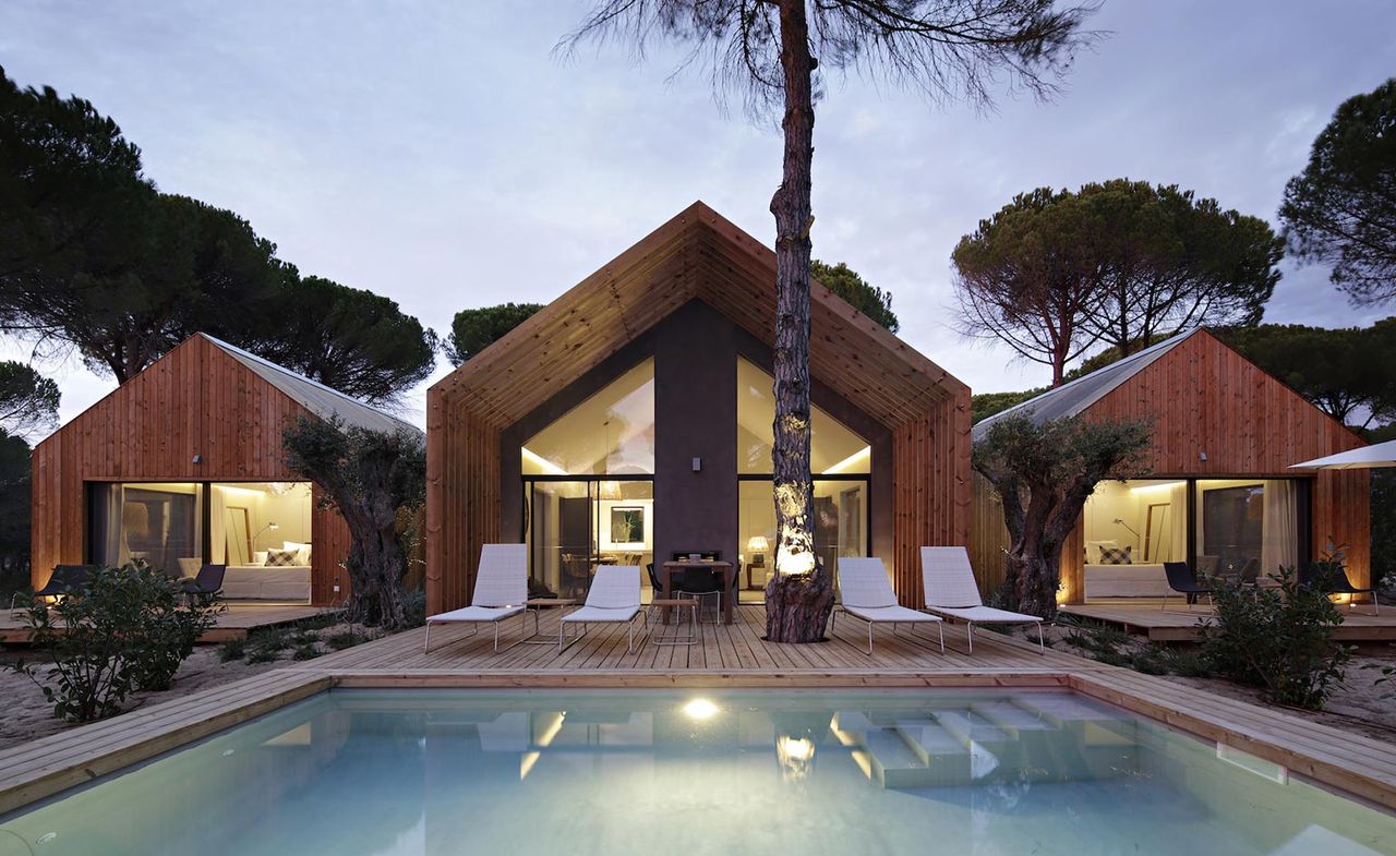 The hotel Sublime Comporta with a beautiful wooden deck and four white swimming pool loungers overlooking the swimming pool