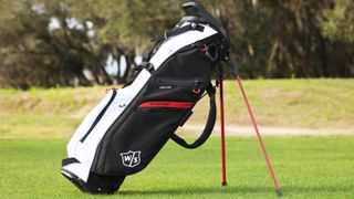 The red and white Wilson Exo Lite Stand Bag resting on the golf course