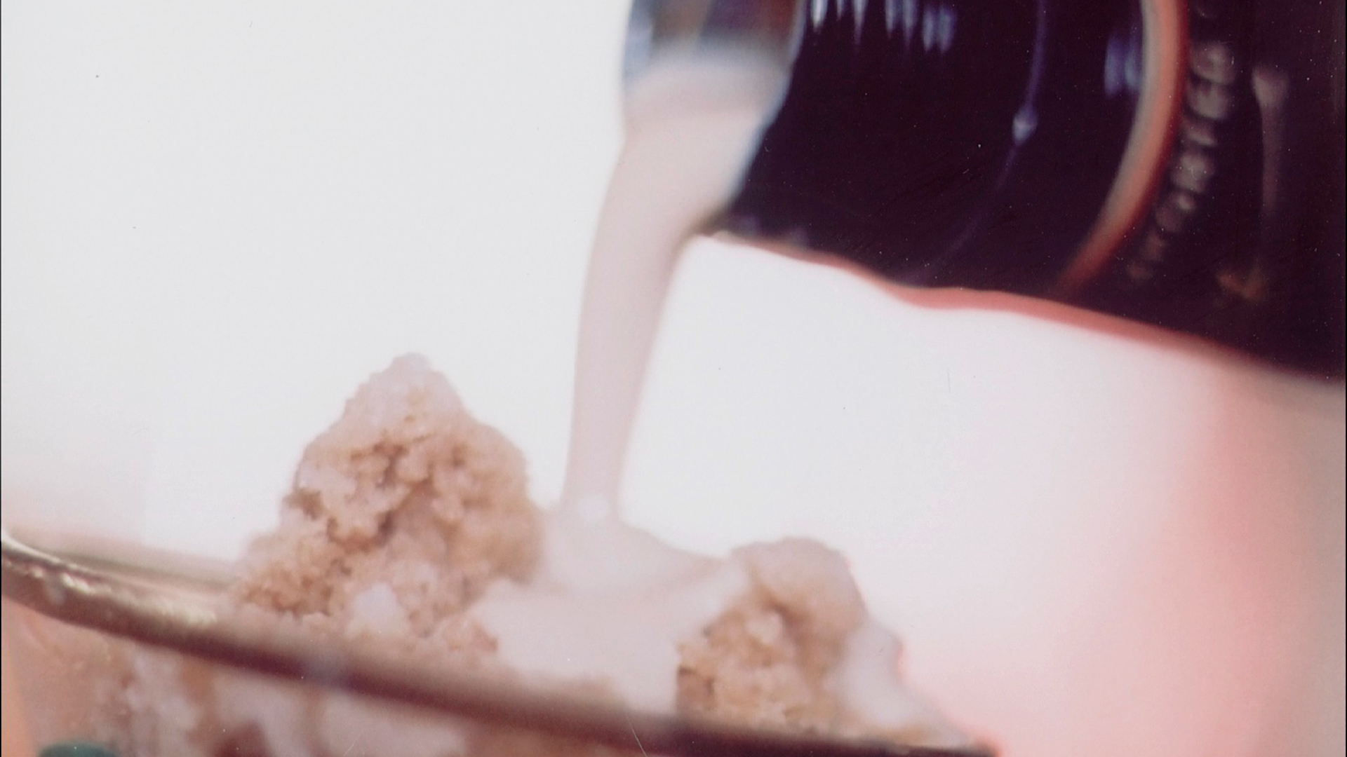 bottle of Baileys being poured over a latte coffee