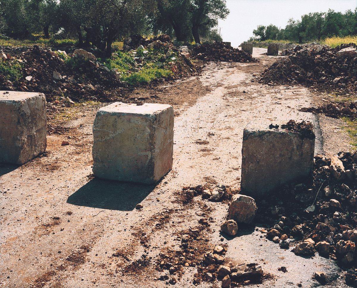 An image by Sophie Ristelhueber of square concrete blocking off a road
