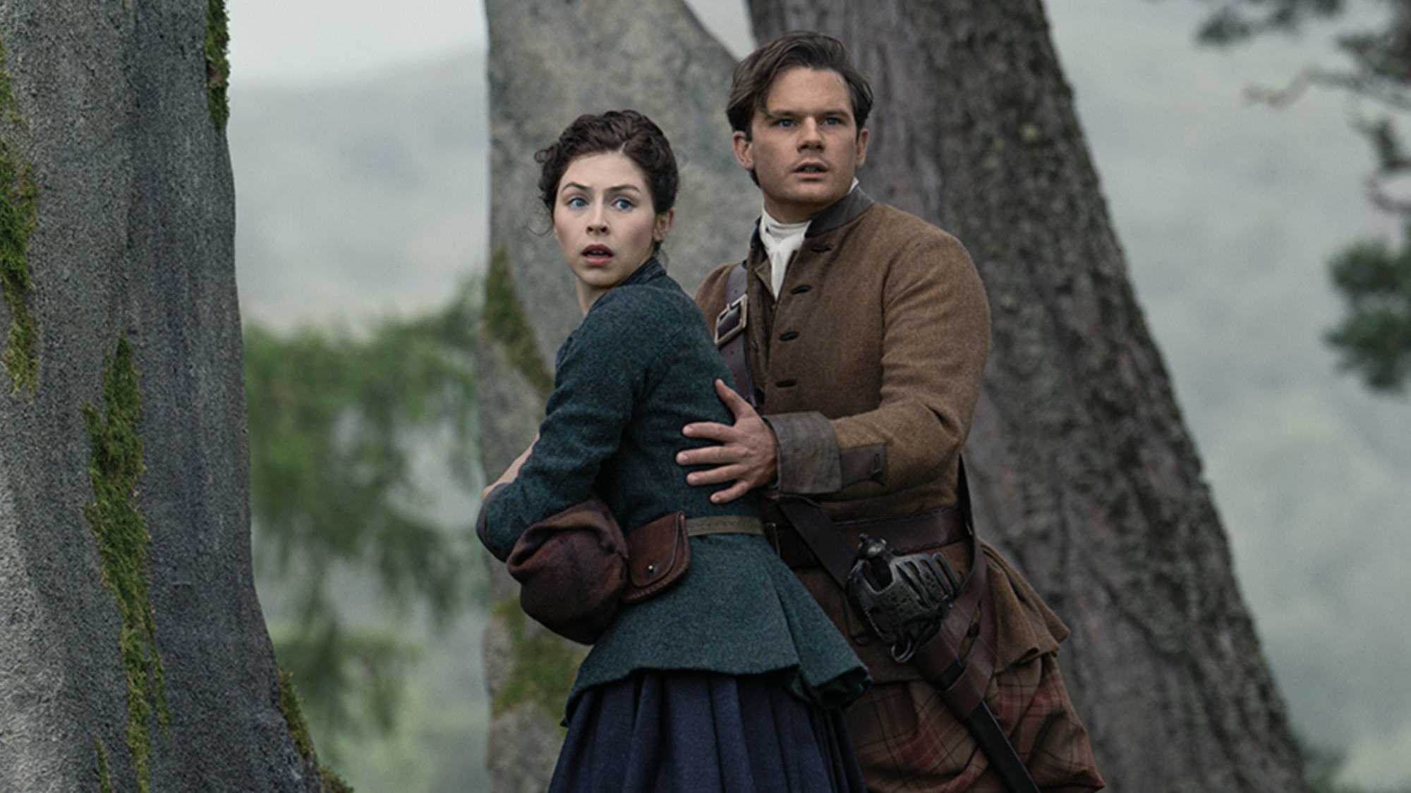 Julia and Henry looking scared, as Henry holds her from behind. 
