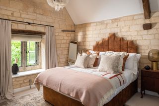 Master bedroom with exposed brick walls and orange headboard