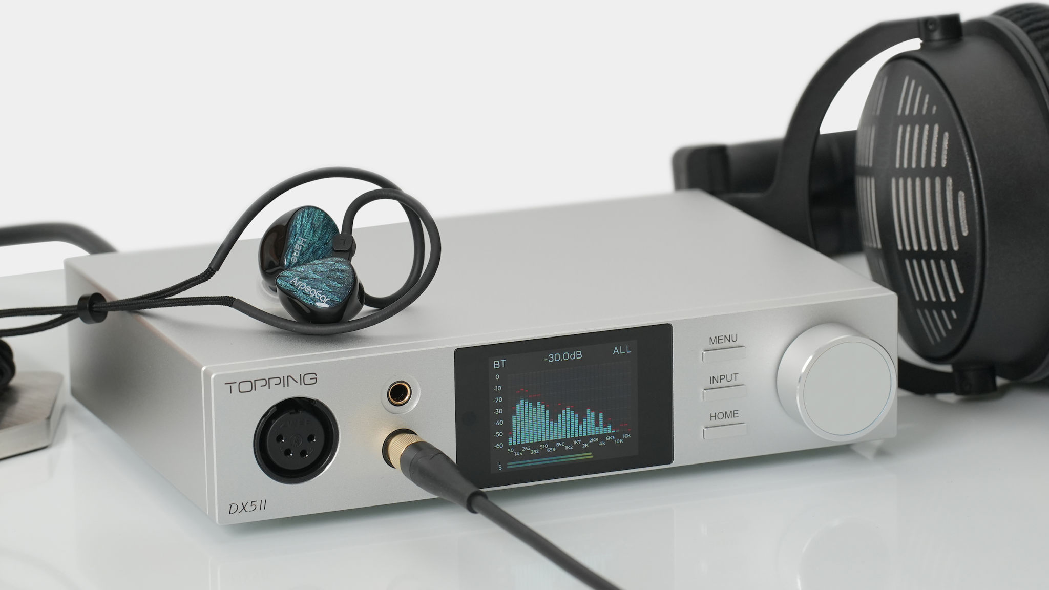 Topping DX5 II on a light coloured surface with headphones to one side and IEMs on top of it