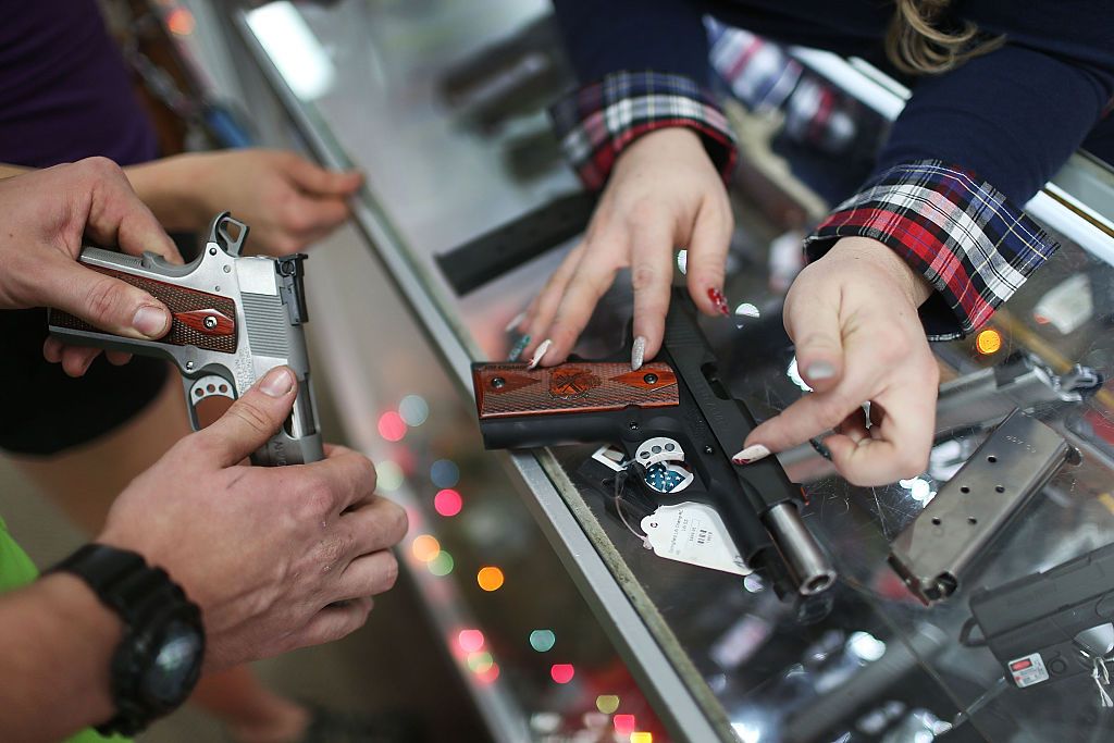 A customer compares handguns before buying one as a Christmas present at the National Armory gun store on December 23, 2015 in Pompano Beach, Florida