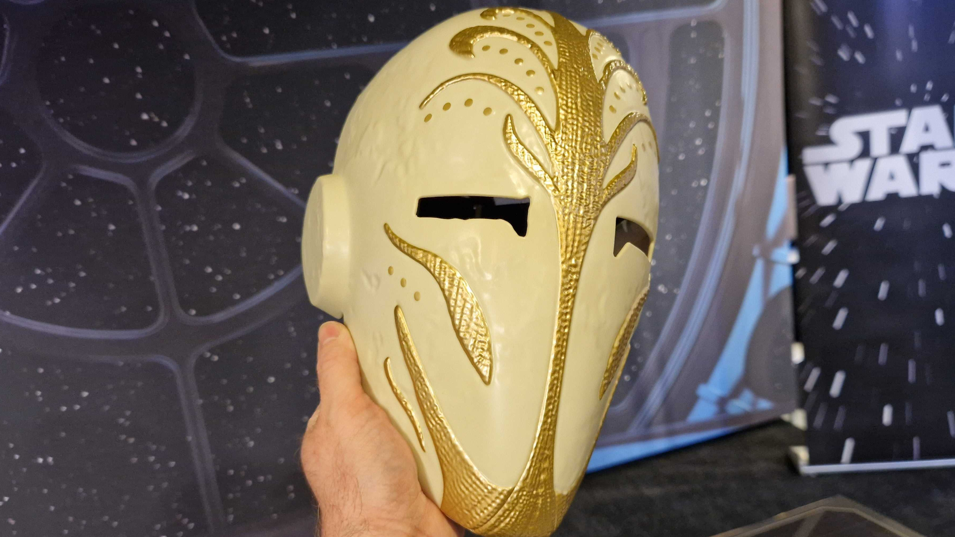 A hand holds the Jedi Temple Guard Mask against a starry background