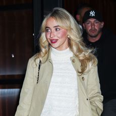 Sabrina Carpenter wearing a tan trench, cream sweater, and black miniskirt out to dinner with Taylor Swift