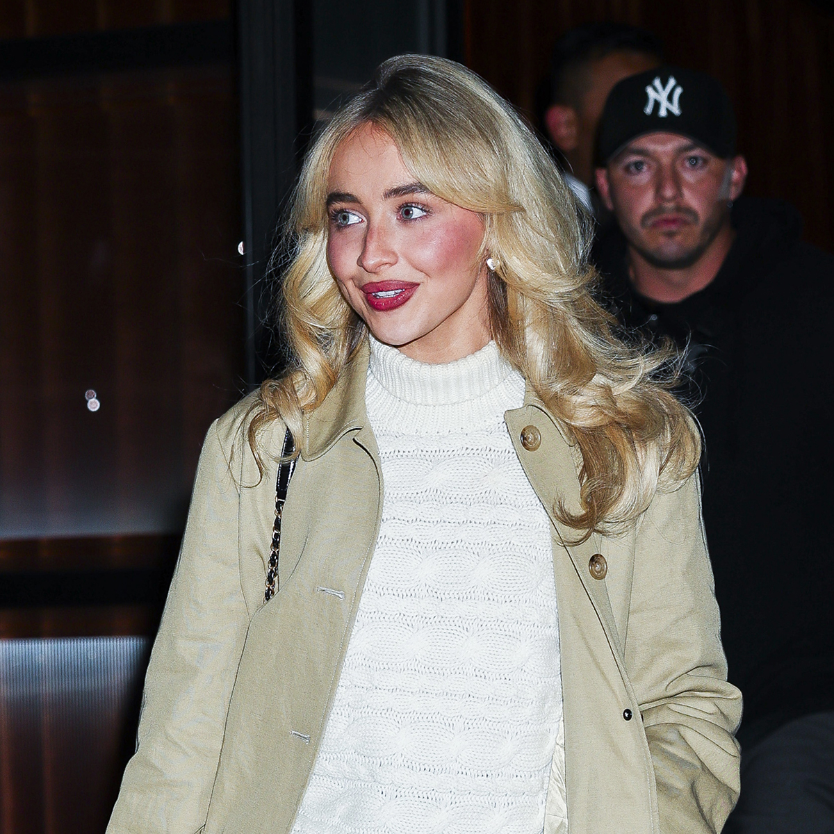 Sabrina Carpenter wearing a tan trench, cream sweater, and black miniskirt out to dinner with Taylor Swift