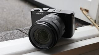 Panasonic Lumix S9 camera with a lens attached balanced on a windowsill