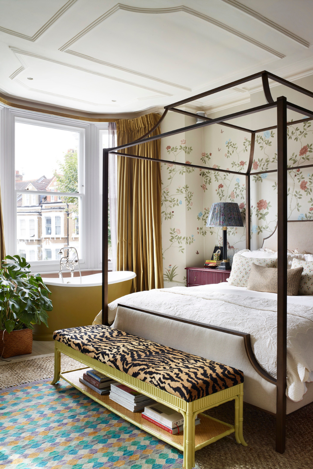 Ecclectic bedroom featuring a yellow tub, four-poster bed frame, and a tiger print-upholstered storage ottoman
