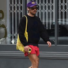 Harry Styles wearing red adidas short shorts and yellow Prada sneakers