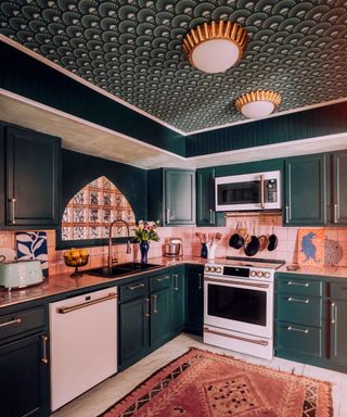 dark green kitchen with ceiling wallpapered with scalloped design in dark green with white details