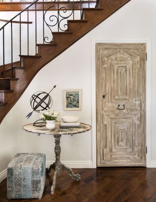White and beige entryway with distressed greige door and decorated round console table for interest