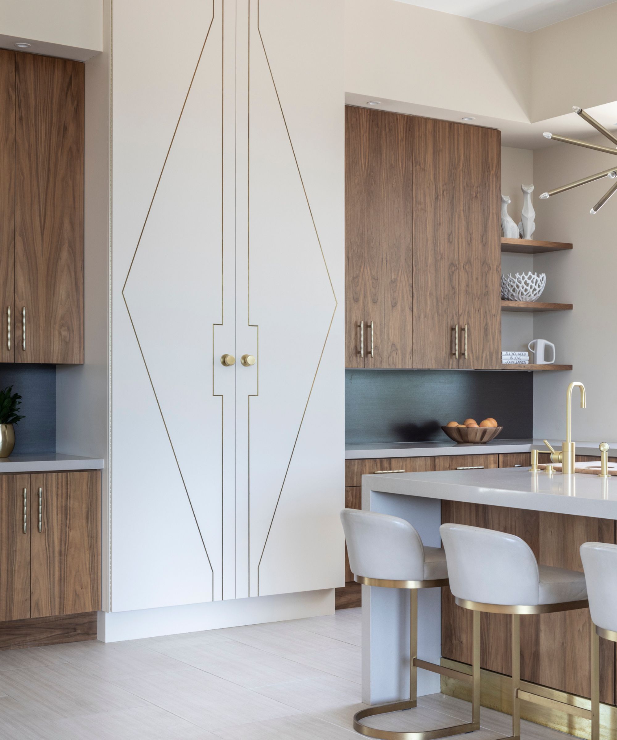 Spacious kitchen with large white fridge with abstract design, brown cabinets, sleek white kitchen island, gold taps, and white floors.