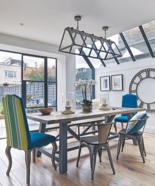 A kitchen extension with a dining table and statement ceiling lighting next to glass doors