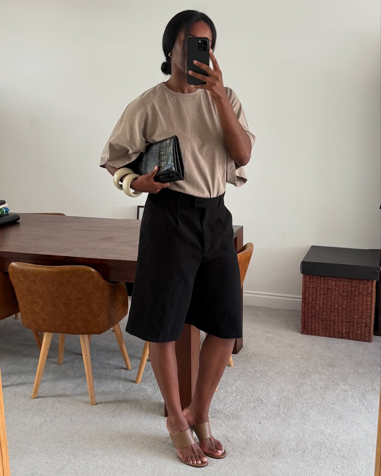 Fashion person Marilyn wears a taupe oversized top, black bermuda shorts '90s inspired t-bar wedges and carries a black croc clutch in a recent image from her Instagram.