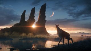 An alien creature on all fours with a slightly long neck and longer front limbs is standing on a pebbled shore by a lake. In the distance there is a mountain with three distinct tall spikes. The sky is darkening, and you can see both the setting sun and a crescent moon.