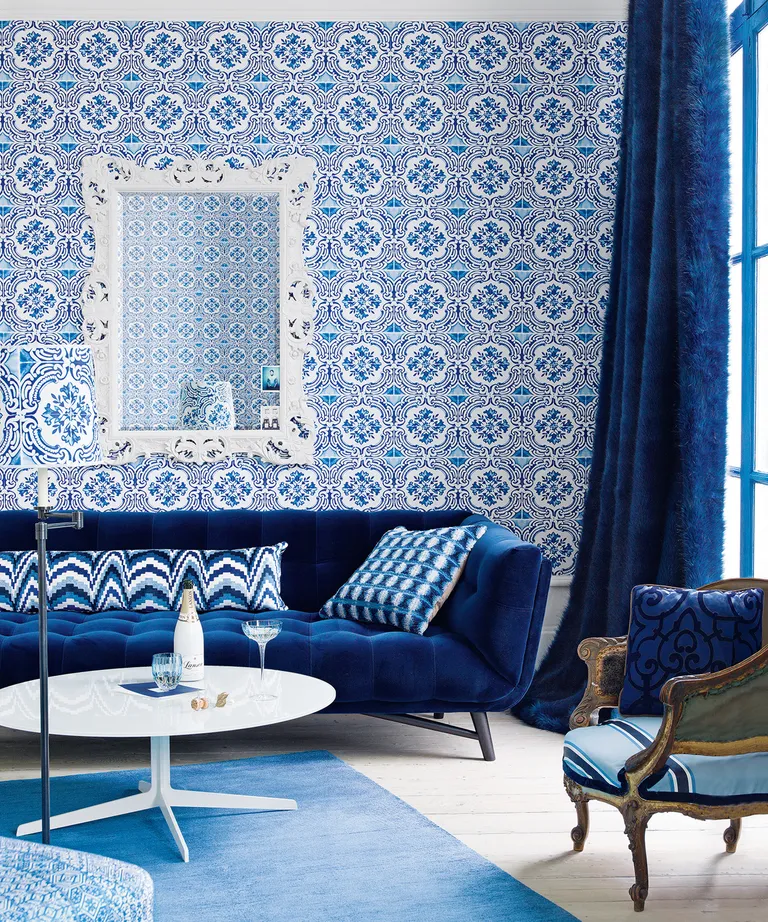 A living room with a dark blue sofa and wallpaper in the style of Portuguese blue and white tiles