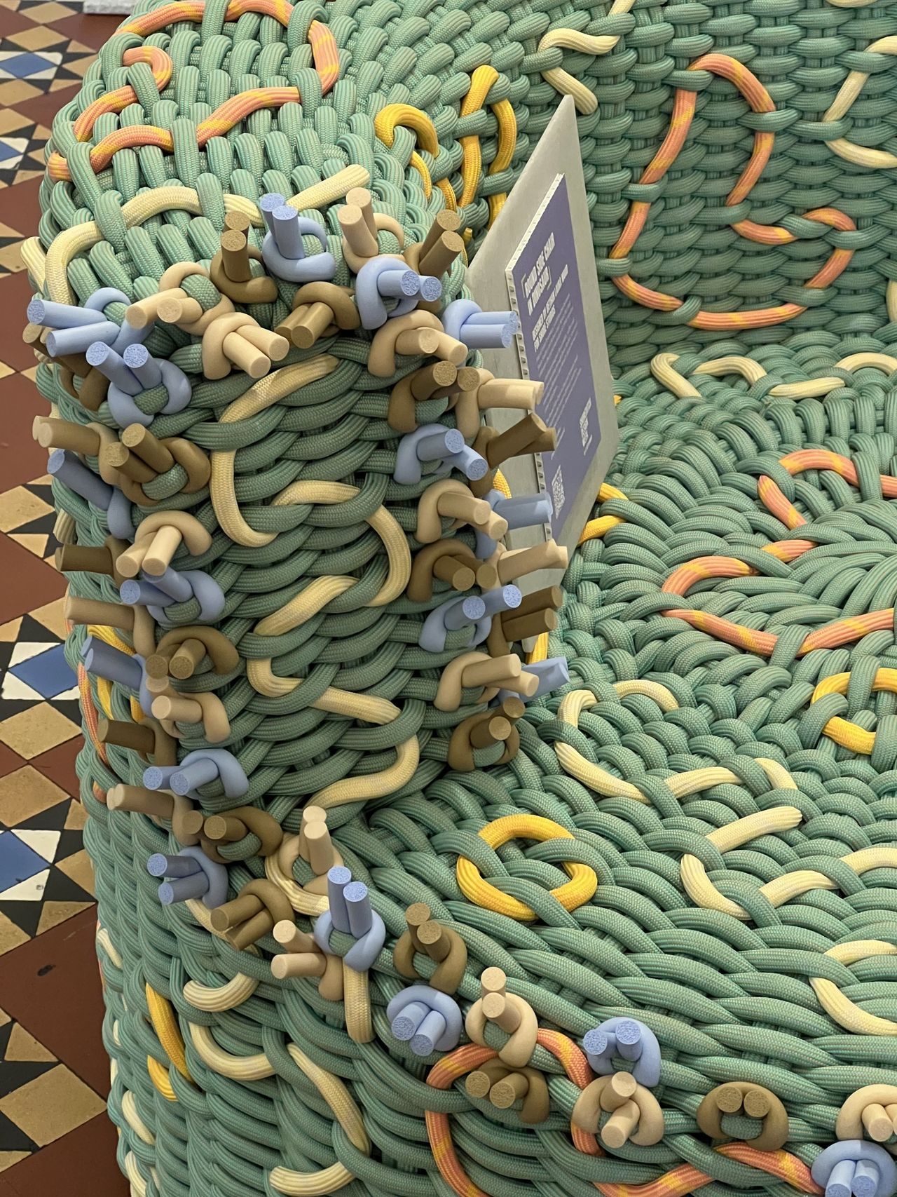 Close-up image of an accent chair woven out of green, purple, yellow and orange rope.