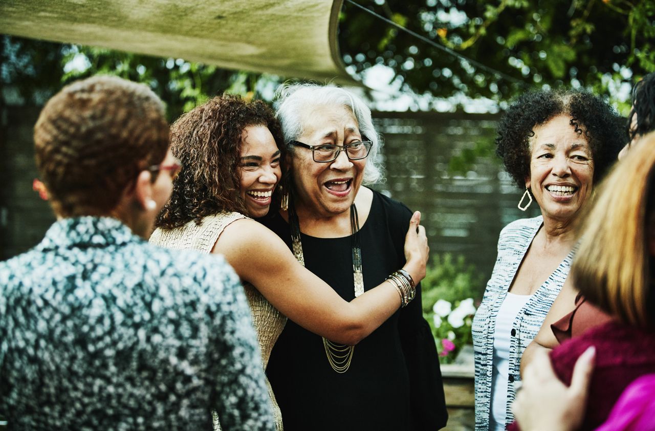 Mature daughter embracing mother after outdoor family dinner party