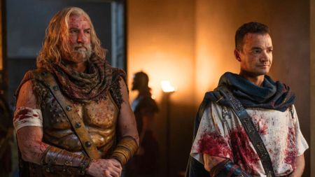 Korris and Ashur stand next to each other covered in blood