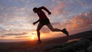 Man trail running at sunset