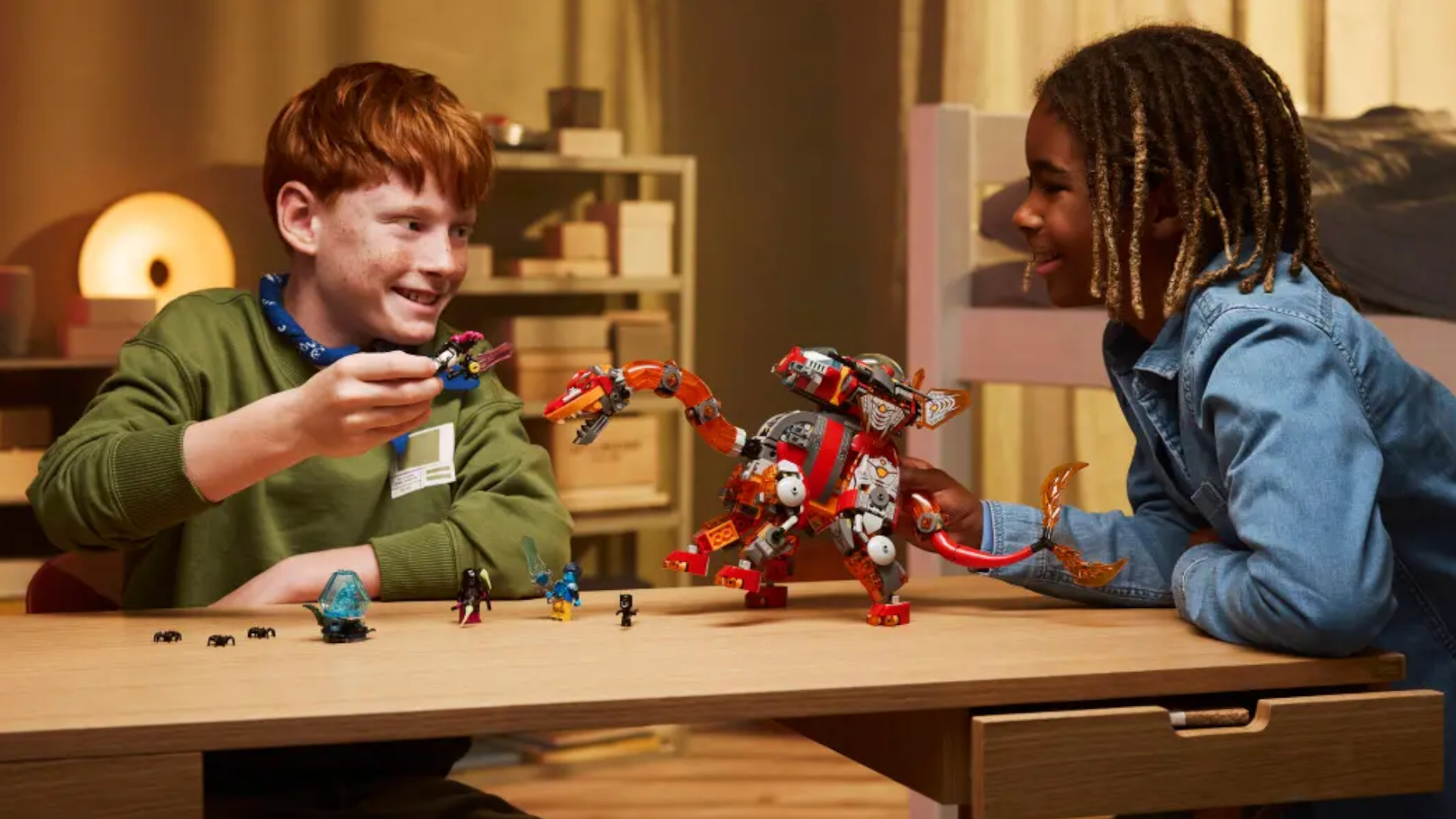 Two children smile while playing with a Lego robot dinosaur and figures at a table