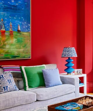A living room with a red wall and a grey sofa