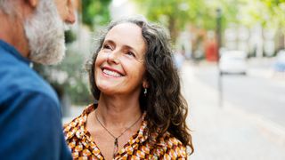 Woman looking up at man standing in the street with smile