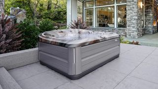A Jacuzzi J-485™ Hot Tub in a modern backyard patio