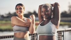 Are sports bras bad for you? Image shows two women in sports bras outdoors stretching and smiling