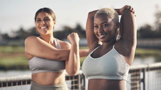 Are sports bras bad for you? Image shows two women in sports bras outdoors stretching and smiling