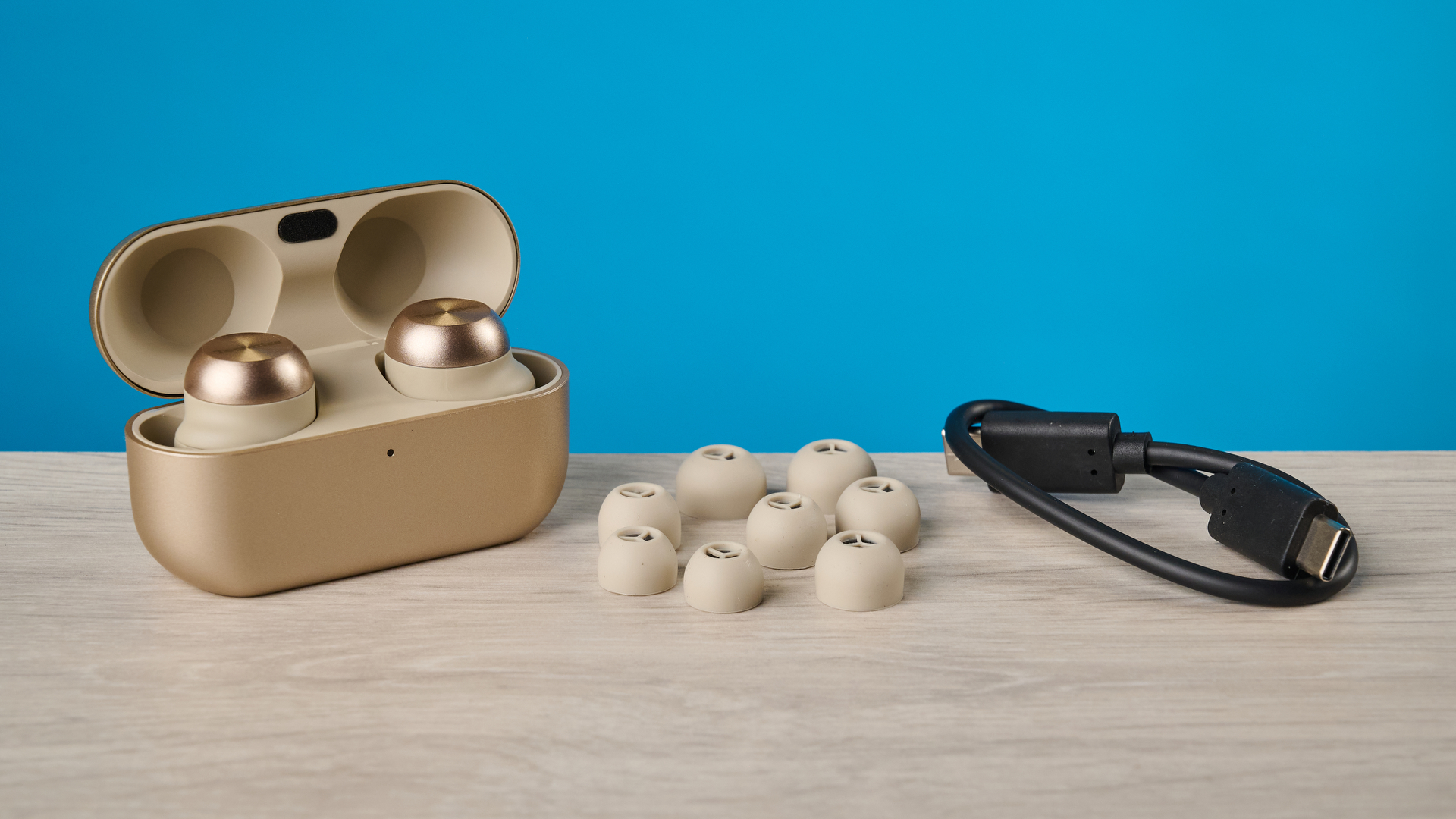 the technics az100 earbuds in champagne photographed against a blue tom's guide background