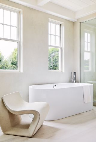 A bathroom with white bathtub and textured walls and chair