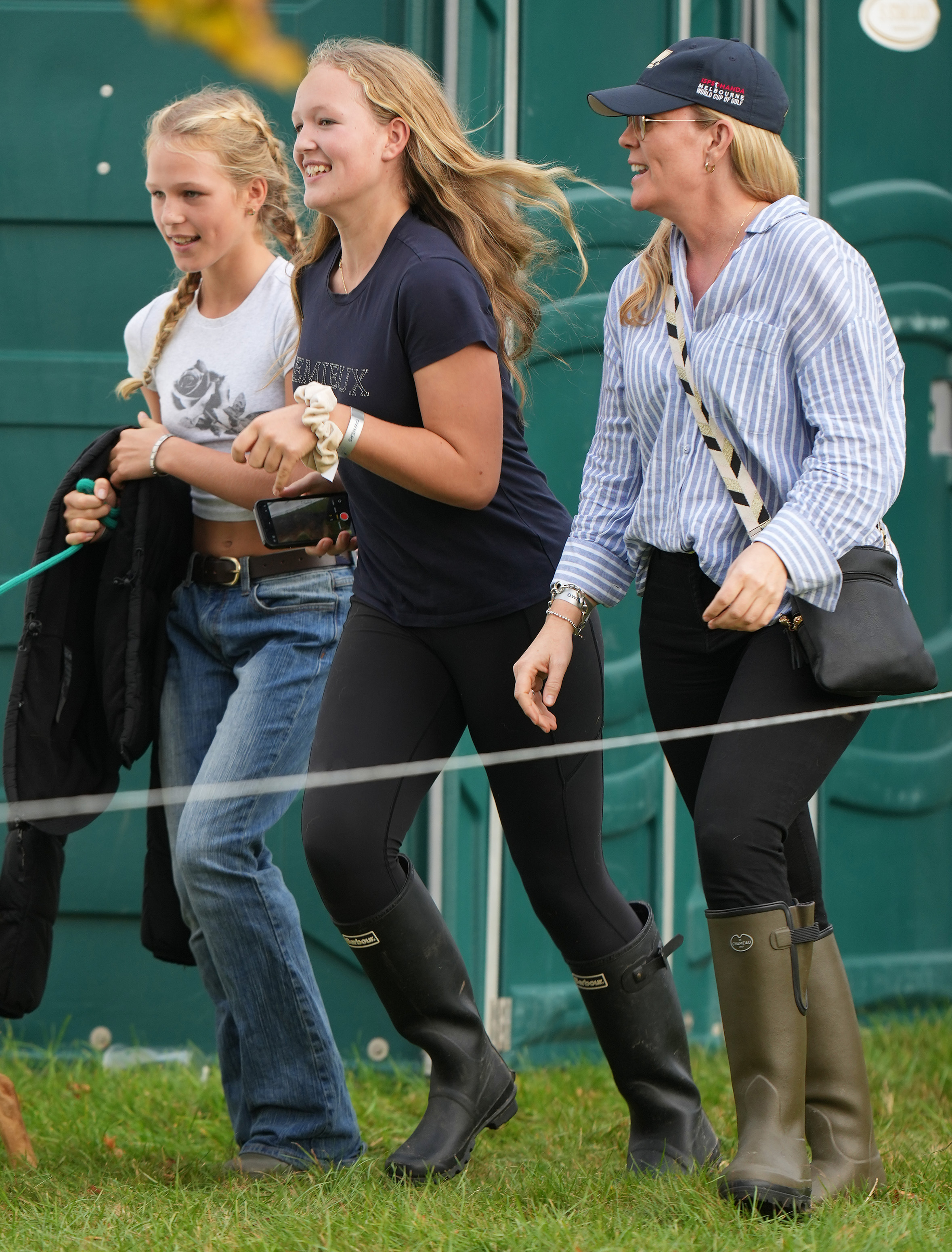 Isla Phillips, Savannah Phillips, Autumn Kelly walking in a row and wearing wellies