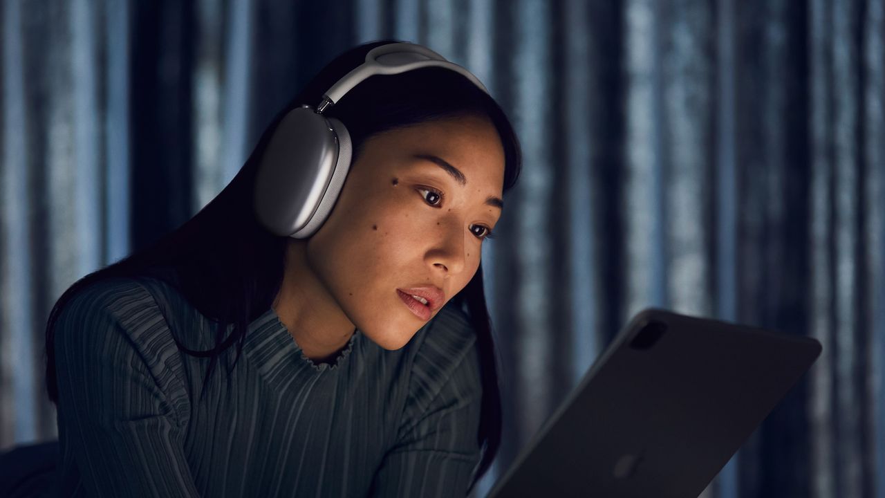 Apple AirPods Max being worn by a woman looking at an iPad