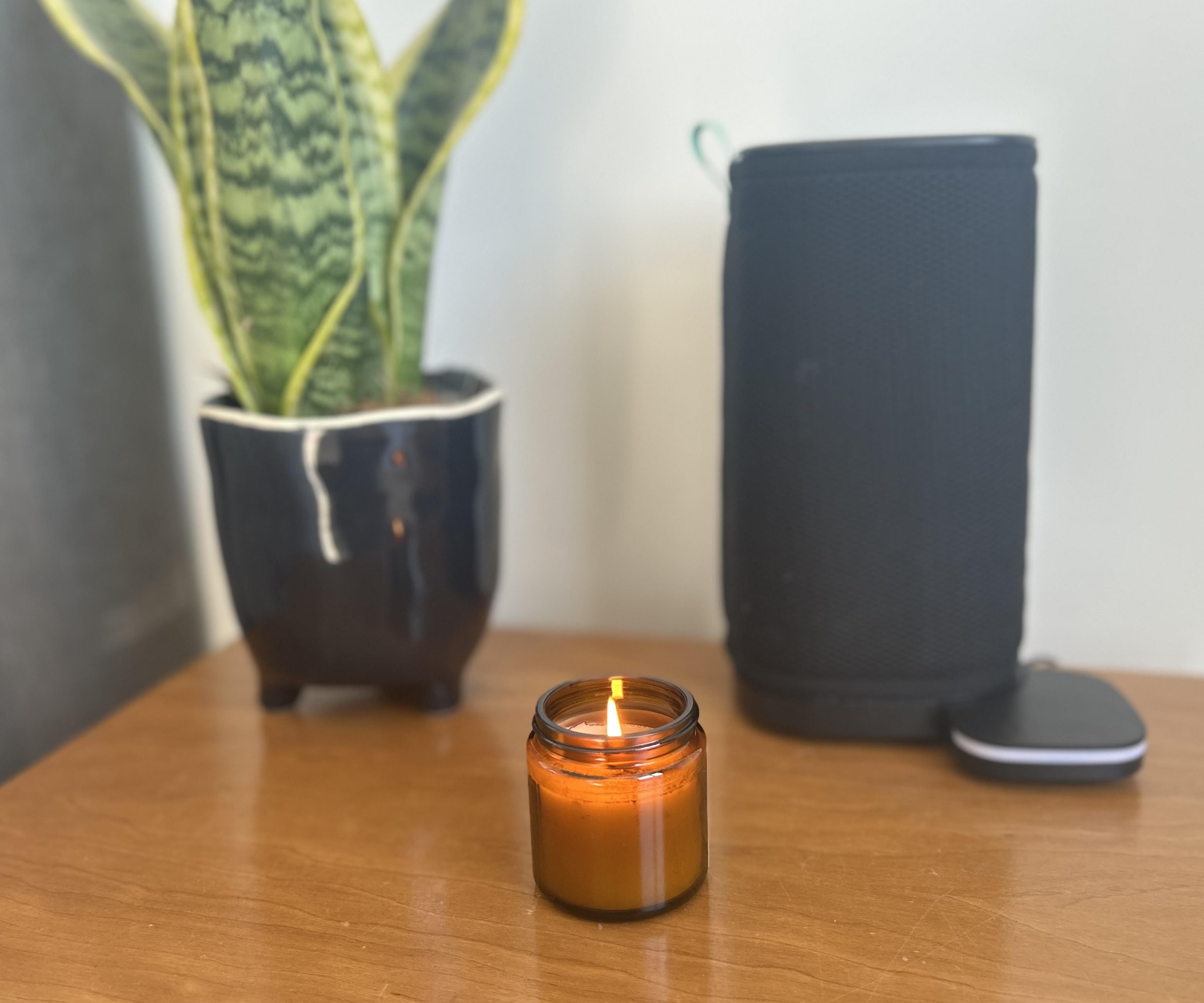 Candle, air purifier and plant on a wooden table