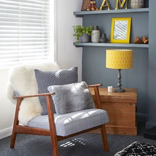 Corner of grey and white living room with chair and open shelving