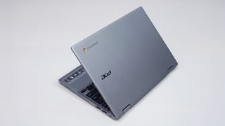 A silver laptop against a white background, its lid halfway open with the brand logo facing the camera.