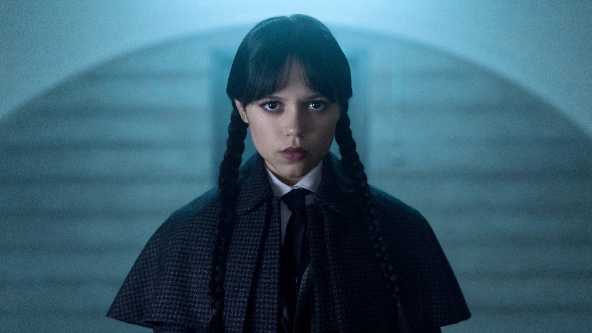 Jenna Ortega as Wednesday Addams looking serious in her Sherlock Holmes coat.