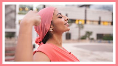 Pretty with pink cancer scarf woman with raised arms showing muscle 
