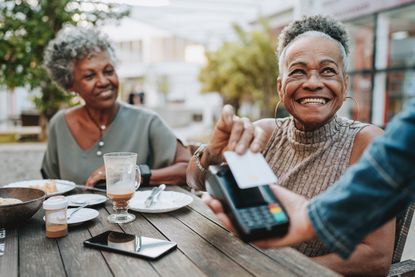 Senior women paying the bill with a credit card at a cafe.