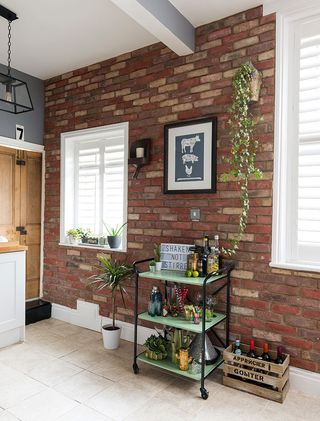 green and black bar trolley next to an exposed brick wall and lots of plants