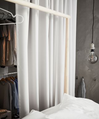 Modern bedroom with open closet, covered in white curtain, bed with white linen