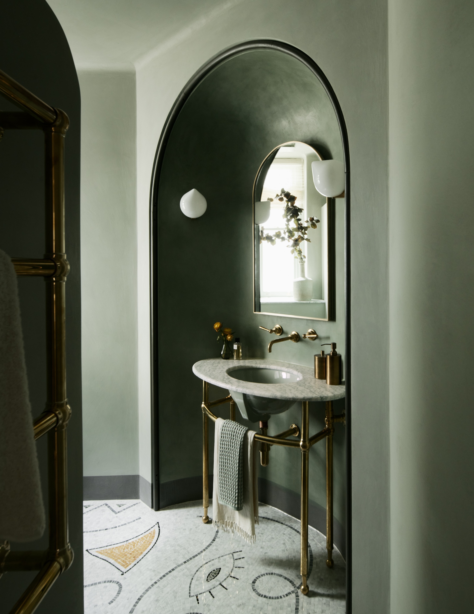 a bathroom with a vanity in an arched alcove with a decorative mosaic floor