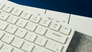 a close up shot of a white wireless bluetooth keyboard resting on a clean white table