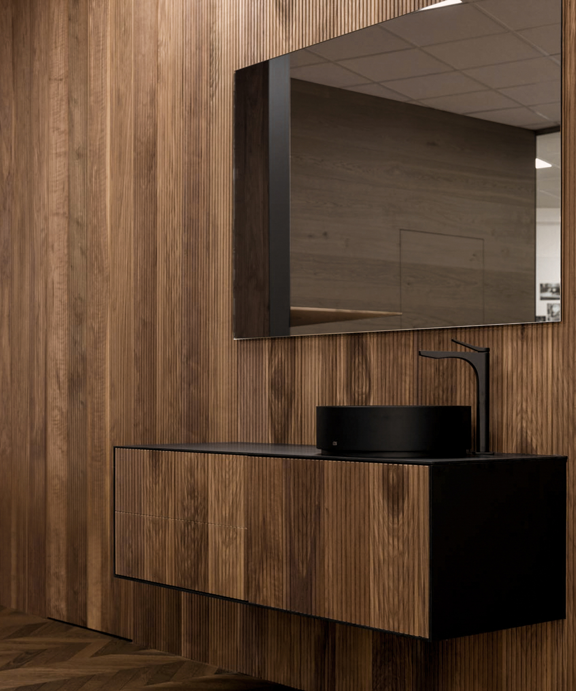 bathroom with wood panelled walls, floors, vanity, large mirror and black sink and tap