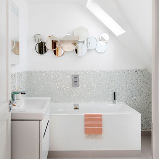 attic bathroom with bathtub and circular mirrors