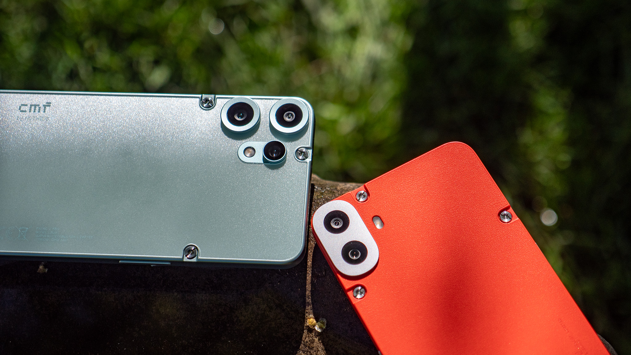 Comparing the backs and camera lenses of the orange CMF Phone 1 to the teal CMF Phone 2 Pro