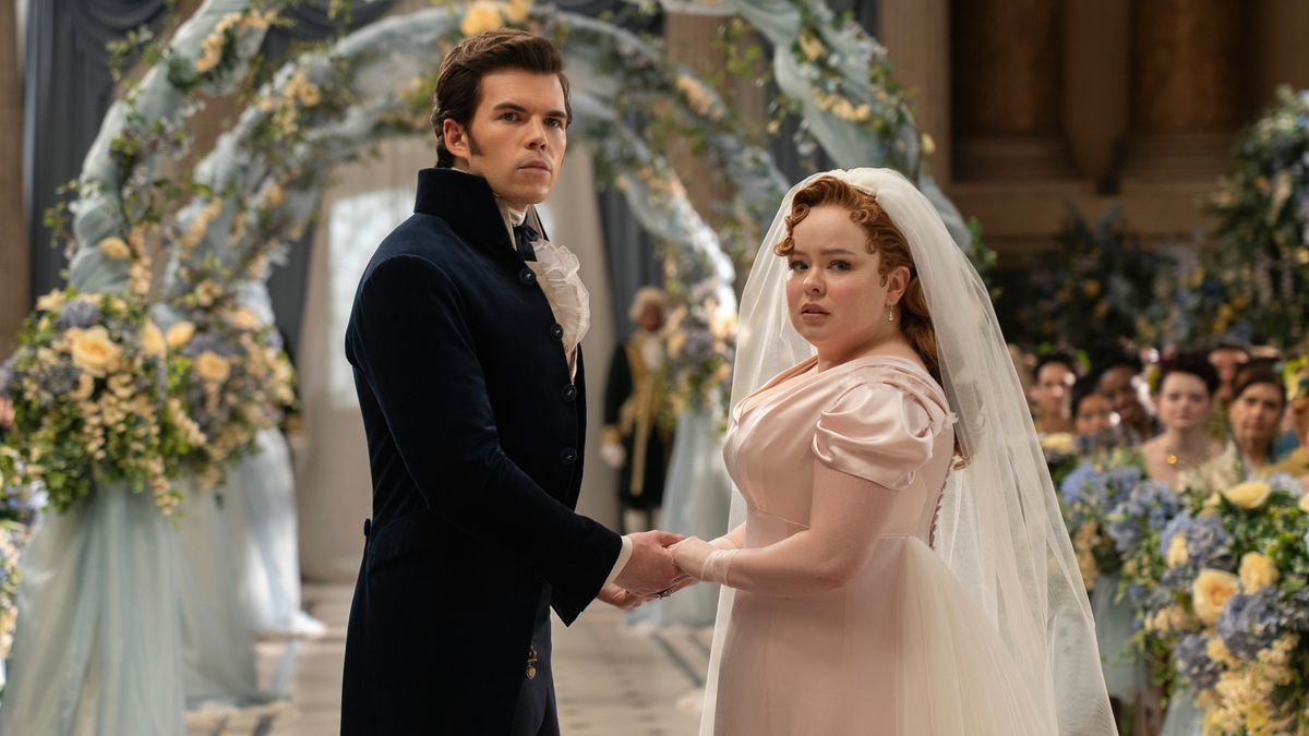 Colin Bridgerton (Luke Newton) and Penelope Featherington (Nicola Coughla) holding hands in a wedding chapel in &quot;Bridgerton&quot; season 3