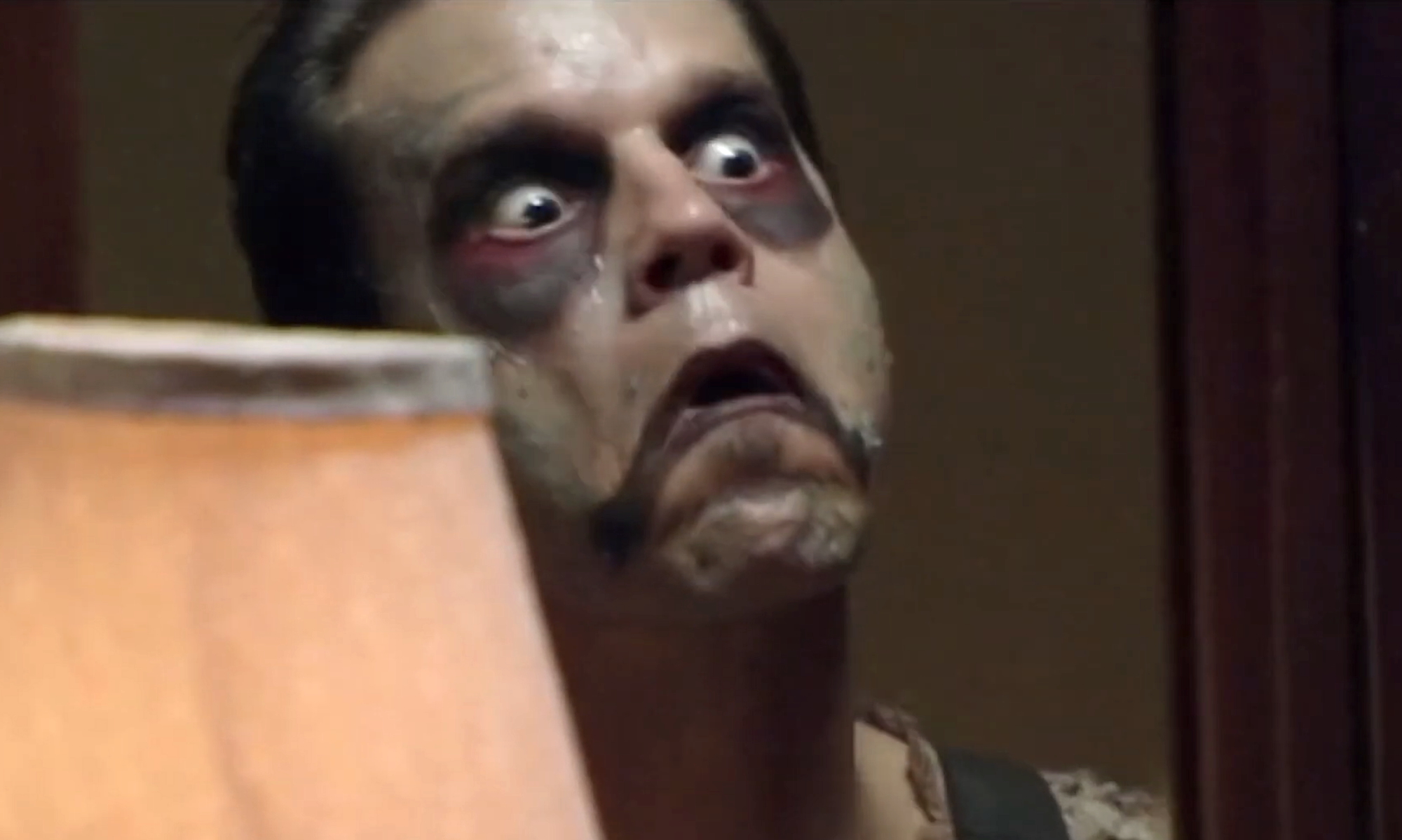 Leslie Vernon making a wide-eyed grimace in the mirror while applying makeup to his face in Behind The Mask: The Rise of Leslie Vernon